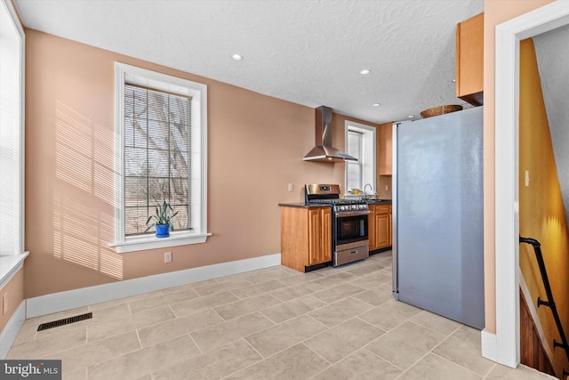 kitchen with visible vents, dark countertops, stainless steel appliances, wall chimney exhaust hood, and baseboards