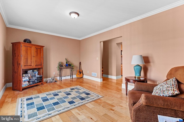 sitting room featuring light wood-style flooring, baseboards, visible vents, and ornamental molding