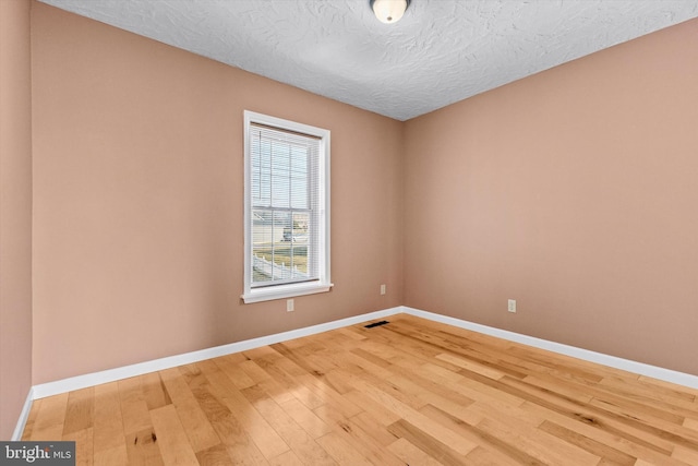 empty room with visible vents, baseboards, and light wood finished floors