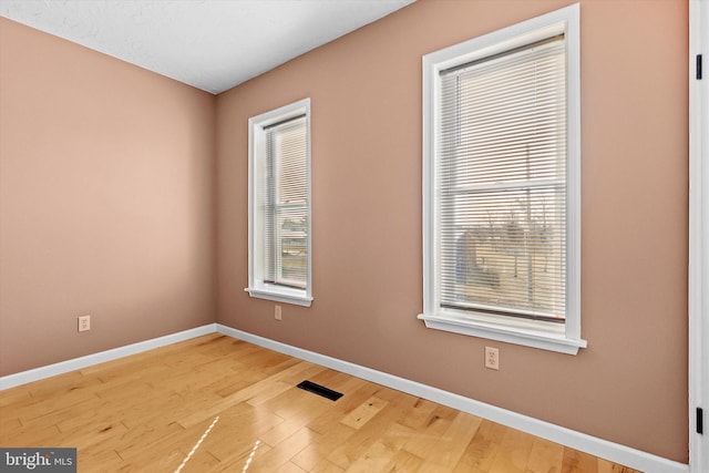 unfurnished room with visible vents, baseboards, and wood finished floors