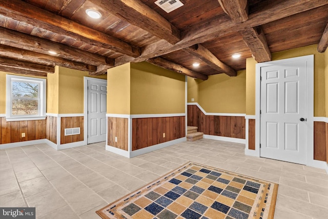 tiled empty room with a wainscoted wall, wood ceiling, and visible vents