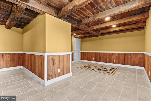 basement with a wainscoted wall, wooden ceiling, and wood walls