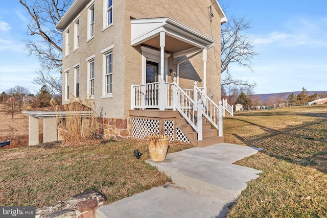 doorway to property featuring a yard and brick siding