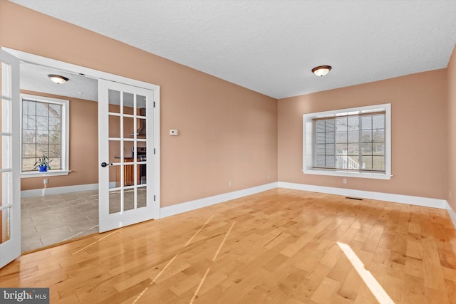 unfurnished room with hardwood / wood-style floors, french doors, visible vents, and baseboards