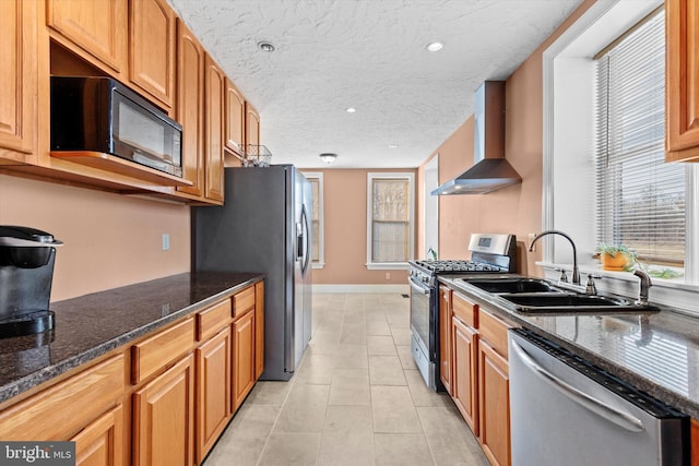 kitchen with light tile patterned floors, a sink, stainless steel appliances, a textured ceiling, and wall chimney range hood