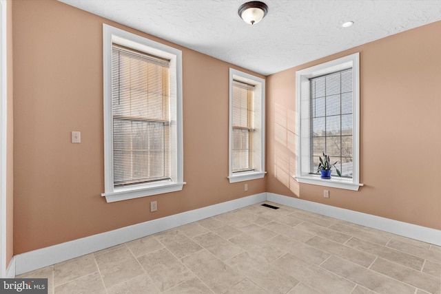 empty room with visible vents, baseboards, and a textured ceiling