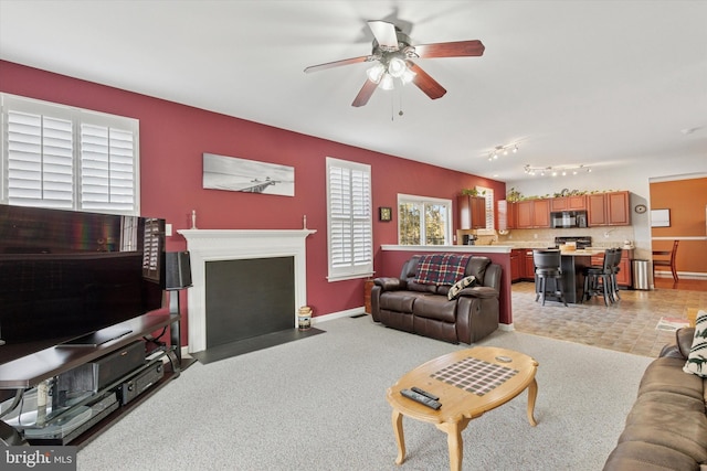 living area featuring a fireplace with flush hearth, baseboards, and a ceiling fan