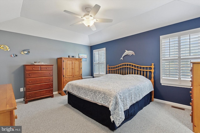 carpeted bedroom featuring visible vents, ceiling fan, baseboards, a tray ceiling, and vaulted ceiling