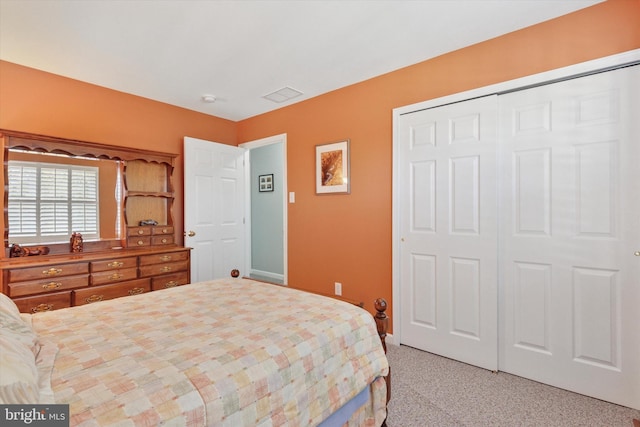 bedroom with a closet, visible vents, and light carpet