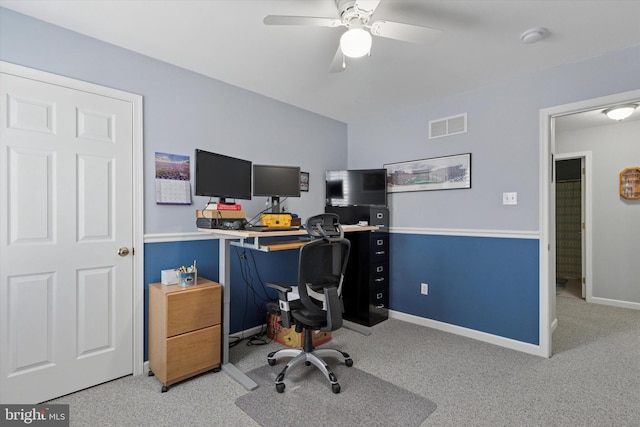 carpeted office space featuring baseboards, visible vents, and ceiling fan