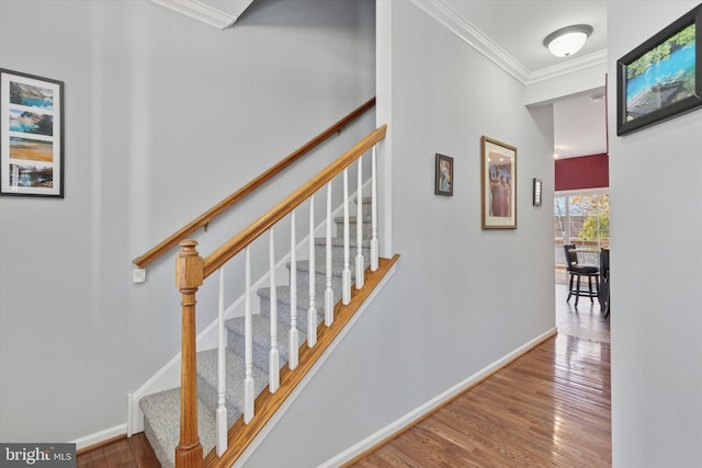 stairway with ornamental molding, baseboards, and wood finished floors