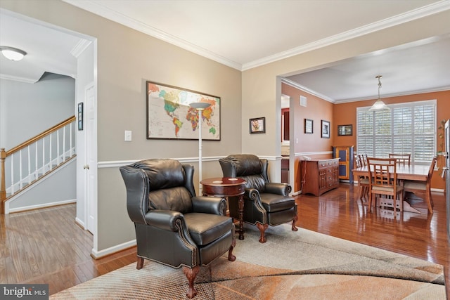 sitting room with stairs, crown molding, and wood finished floors