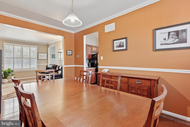 dining room featuring visible vents, crown molding, and baseboards