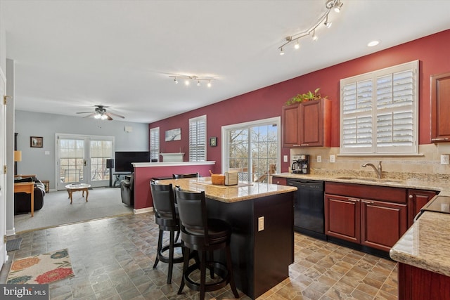 kitchen featuring a sink, a kitchen island, black dishwasher, and plenty of natural light