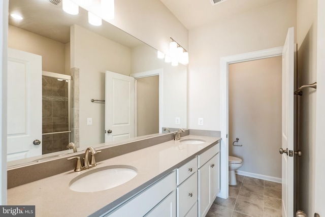 bathroom with a sink, tiled shower, toilet, and double vanity