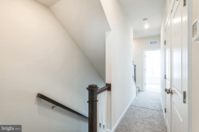 corridor featuring an upstairs landing, visible vents, carpet flooring, and baseboards