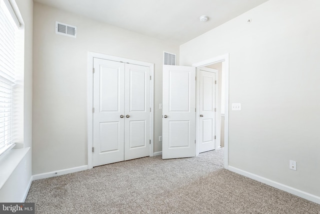 unfurnished bedroom featuring visible vents, baseboards, carpet, and a closet