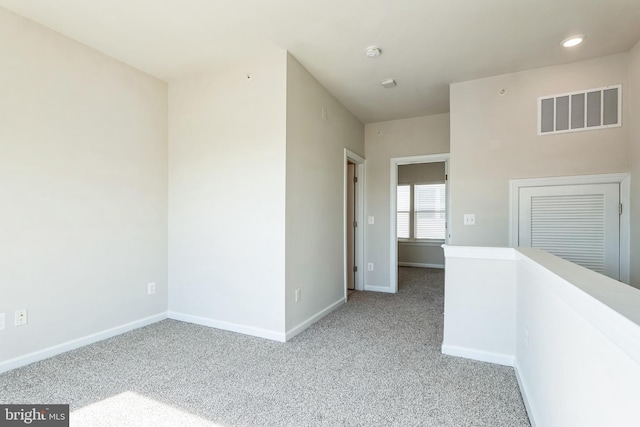 carpeted spare room featuring recessed lighting, baseboards, and visible vents