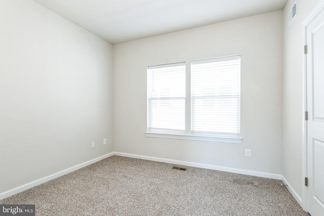 carpeted spare room featuring visible vents and baseboards