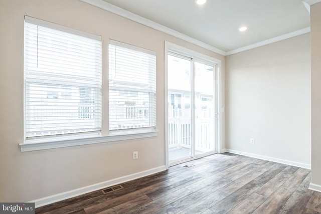 unfurnished room with crown molding, wood finished floors, visible vents, and baseboards