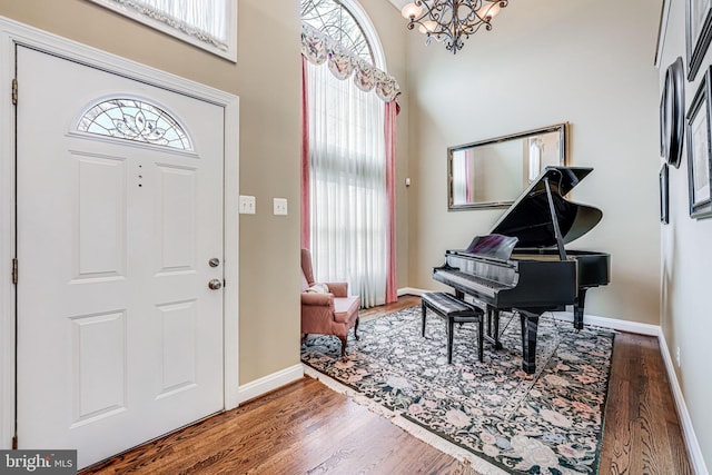 foyer with a chandelier, a high ceiling, baseboards, and wood finished floors