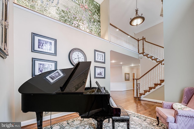 sitting room with wood finished floors, a high ceiling, crown molding, baseboards, and stairs