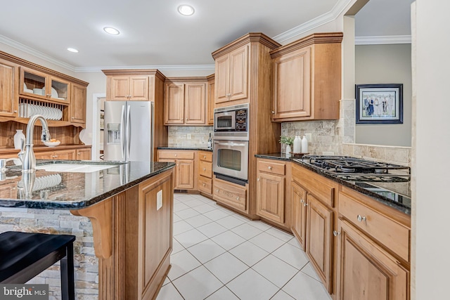 kitchen with a breakfast bar, light tile patterned floors, dark stone countertops, appliances with stainless steel finishes, and a sink