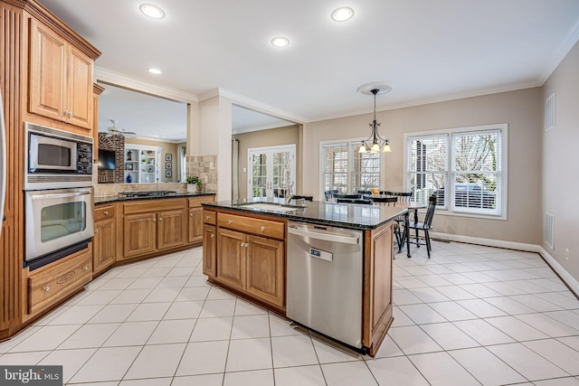 kitchen featuring ornamental molding, a sink, stainless steel appliances, dark stone counters, and light tile patterned floors