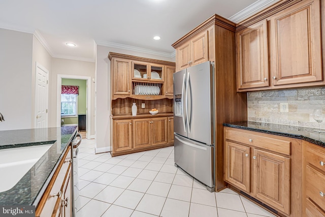 kitchen featuring a sink, dark stone counters, appliances with stainless steel finishes, light tile patterned floors, and decorative backsplash