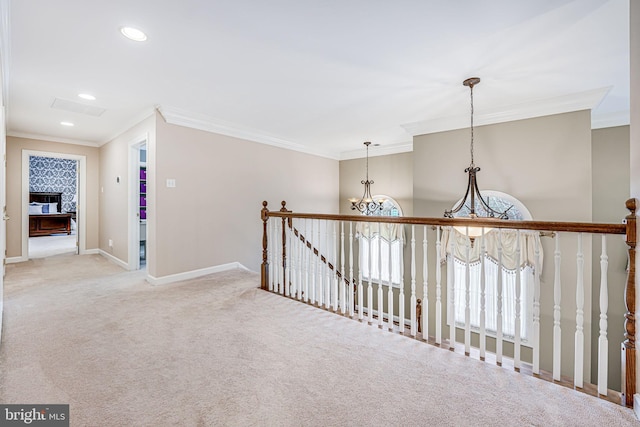 hallway featuring baseboards, ornamental molding, an upstairs landing, light colored carpet, and a chandelier