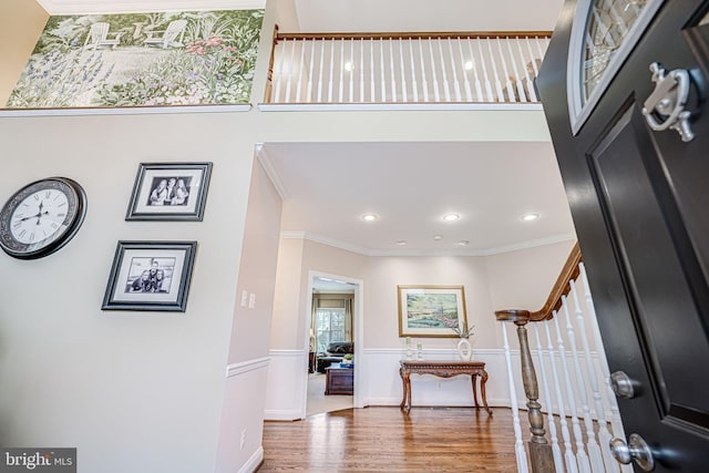 entrance foyer featuring stairs, crown molding, a high ceiling, and wood finished floors