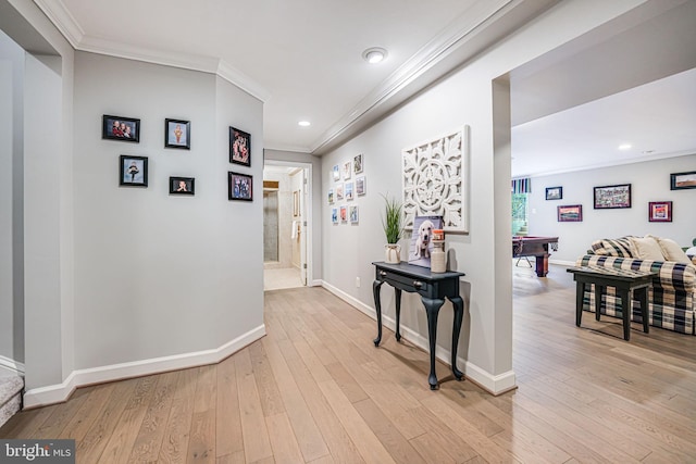 hallway with light wood-style flooring, baseboards, and ornamental molding