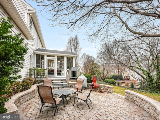 view of patio with a sunroom and an outdoor fire pit