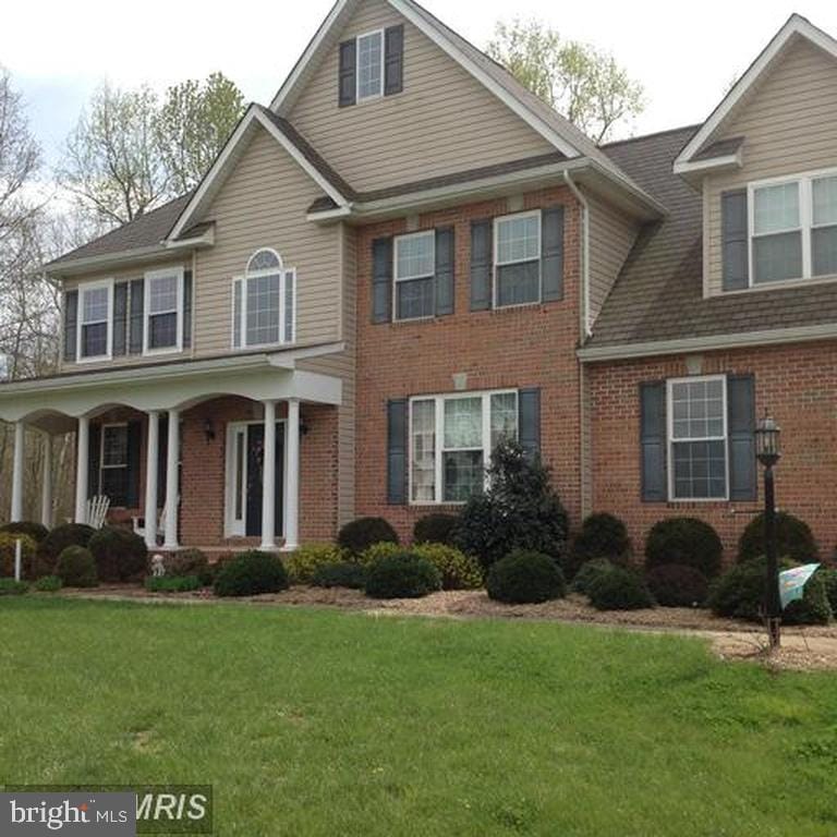 view of front of home featuring brick siding, a porch, and a front yard