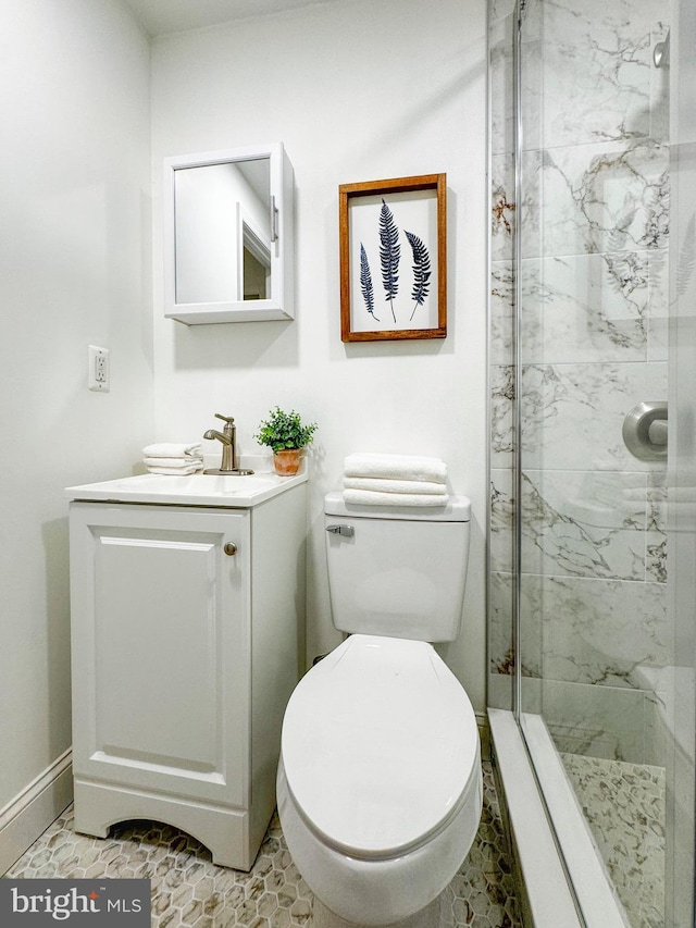 bathroom with a marble finish shower, toilet, and vanity