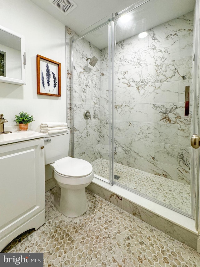 bathroom featuring a marble finish shower, visible vents, toilet, and vanity