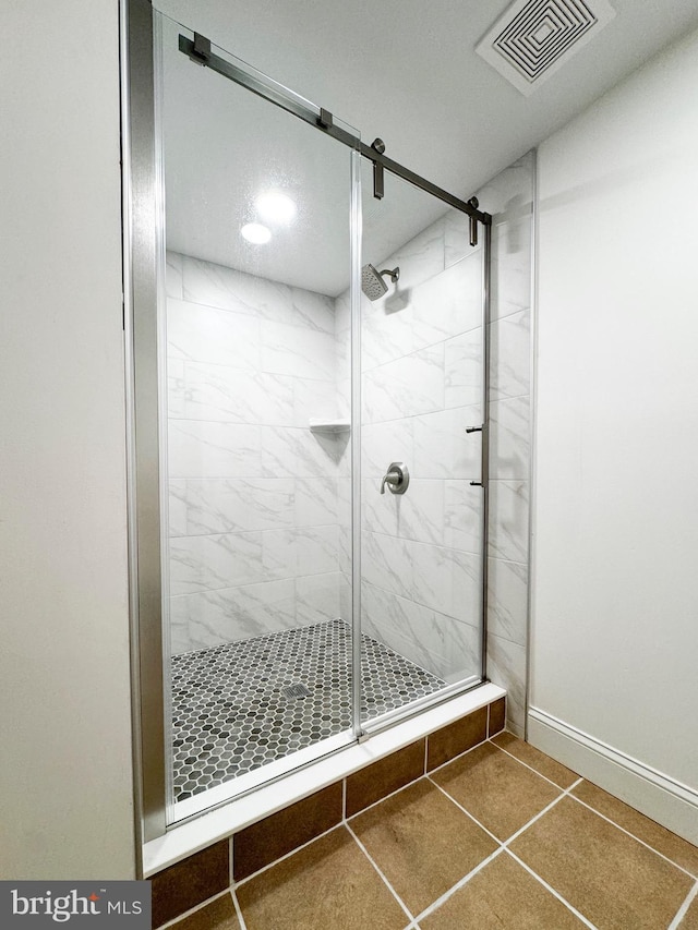 bathroom featuring tile patterned floors, visible vents, a shower stall, and baseboards