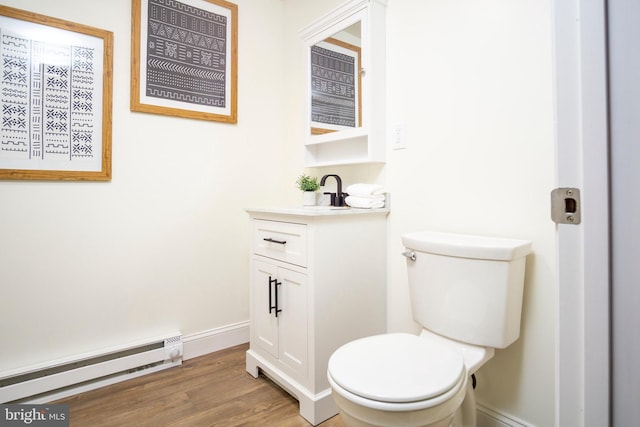 half bath featuring toilet, wood finished floors, baseboards, baseboard heating, and vanity