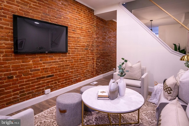 interior space featuring brick wall, baseboards, and wood finished floors