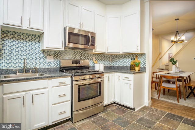 kitchen with dark countertops, tasteful backsplash, stone finish flooring, appliances with stainless steel finishes, and a sink