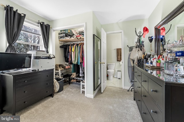 bedroom featuring light carpet, ensuite bath, a closet, baseboards, and a spacious closet