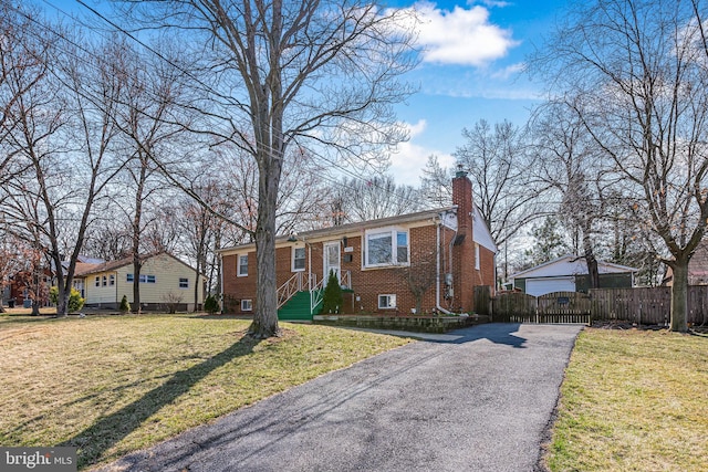 view of front facade with brick siding, a front lawn, fence, a chimney, and a gate