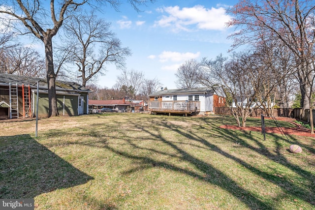 view of yard featuring a wooden deck, an outbuilding, and fence