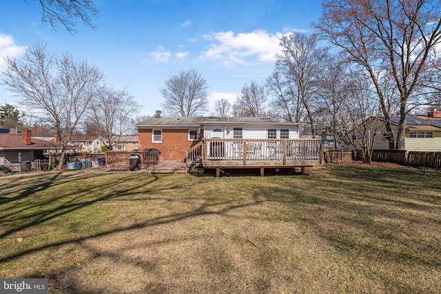 rear view of property featuring brick siding, fence, a lawn, a chimney, and a deck