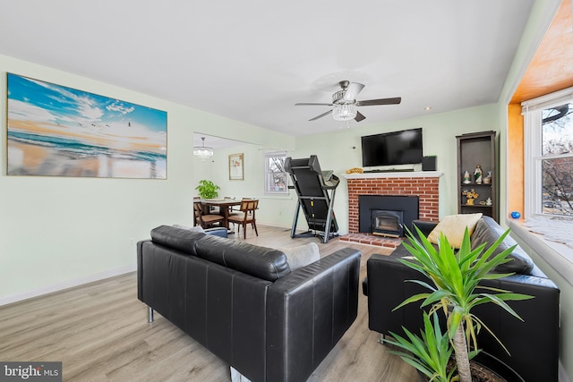 living area with a ceiling fan, baseboards, and light wood-type flooring