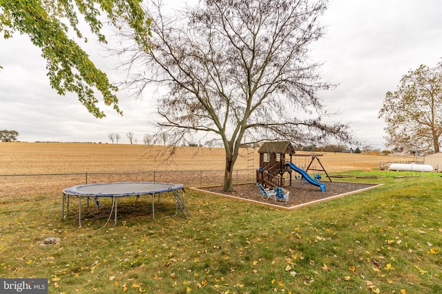 view of yard with a rural view, a playground, a trampoline, and fence