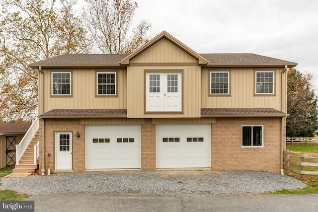 view of front of house with gravel driveway, stairs, and roof with shingles