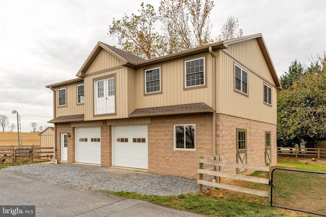 view of front of home with gravel driveway, fence, a garage, and roof with shingles