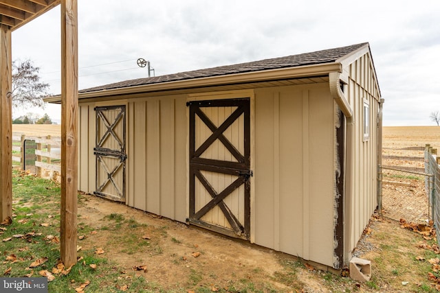 view of shed featuring a rural view and fence