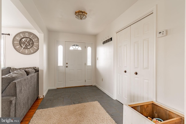 foyer entrance featuring baseboards and stone finish floor